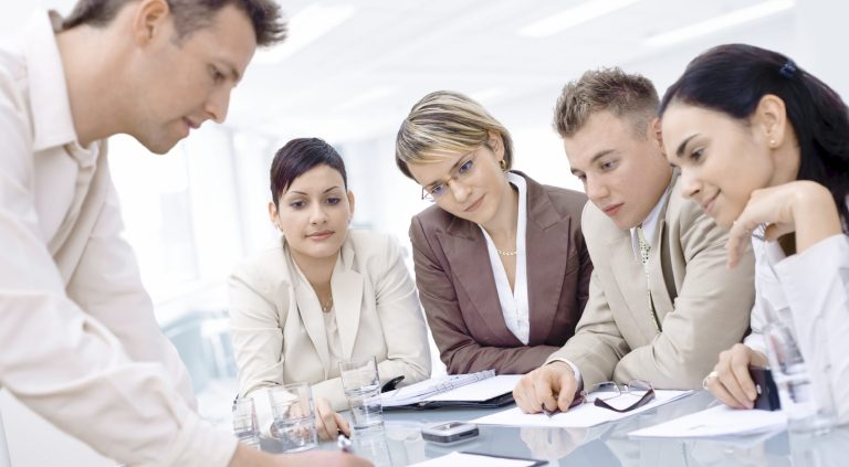 Groupe de professionnels en discussion autour d'une table dans un bureau moderne.